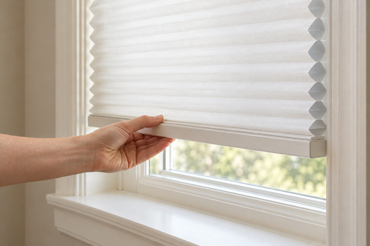 Hand lifting the bottom rail of a white cordless cellular shade